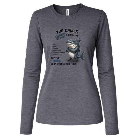 A women's long-sleeve crewneck t-shirt in deep heather, featuring a graphic print of a shark with crossed arms and the text 'YOU CALL IT OCD I CALL IT.' along with a checklist and the phrase 'PUT THE TRICKS BACK WHERE I HAD THEM!' on a transparent background