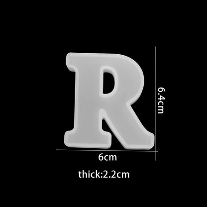 White letter 'R' with measurements on a black background 6cm wide, 6.4cm high 2.2cm thick