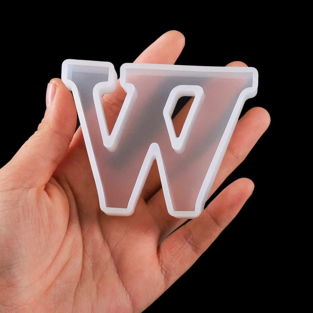 Clear plastic letter 'W' mold held in a hand against a black background