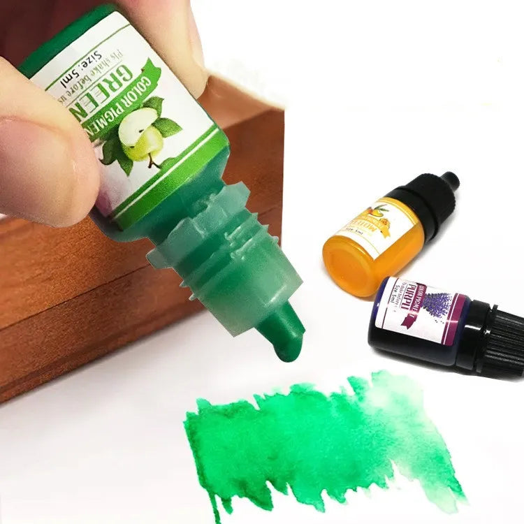 Green bottle of acrylic resin dyet being squeezed with a wooden surface and other bottles in the background