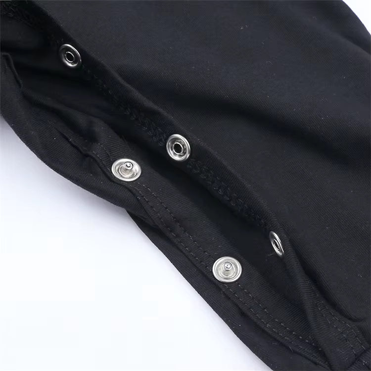 Close-up of a black garment with silver metal snap buttons along a seam, photographed on a white background.