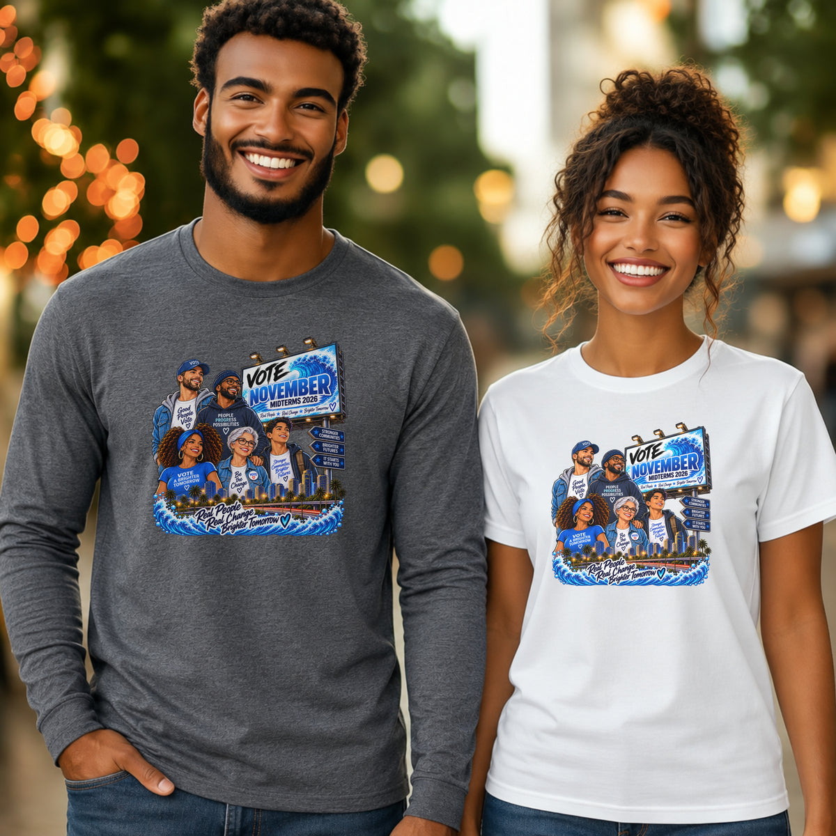 A man and a woman standing side by side outdoors, each wearing a graphic T-shirt. The man wears a dark heather gray long-sleeve shirt with a large 'VOTE NOVEMBER' illustration, and the woman wears a white short-sleeve T-shirt with the same graphic.