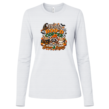 White Halloween coffee design log sleeve shirt featuring a cozy raccoon in an orange knit hat and scarf surrounded by pumpkin spice drinks, pumpkins, bats, and autumn leaves, with the text “Freshly Boo'd Coffee” and “Scream & Sugar” on a transparent background