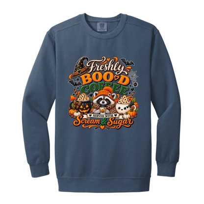 Blue Jean Halloween coffee design sweatshirt featuring a cozy raccoon in an orange knit hat and scarf surrounded by pumpkin spice drinks, pumpkins, bats, and autumn leaves, with the text “Freshly Boo'd Coffee” and “Scream & Sugar” on a transparent background
