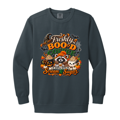 Denim Halloween coffee design sweatshirt featuring a cozy raccoon in an orange knit hat and scarf surrounded by pumpkin spice drinks, pumpkins, bats, and autumn leaves, with the text “Freshly Boo'd Coffee” and “Scream & Sugar” on a transparent background