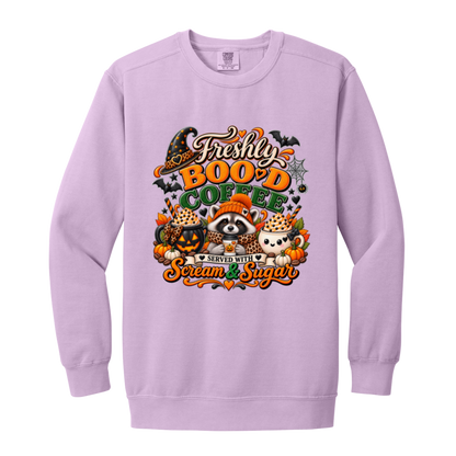 Orchid Halloween coffee design sweatshirt featuring a cozy raccoon in an orange knit hat and scarf surrounded by pumpkin spice drinks, pumpkins, bats, and autumn leaves, with the text “Freshly Boo'd Coffee” and “Scream & Sugar” on a transparent background