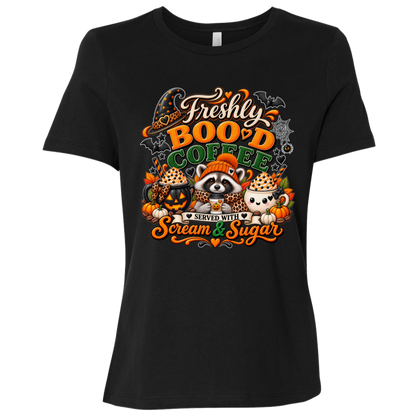 Black Halloween coffee t-shirt design featuring a cozy raccoon in an orange knit hat and scarf surrounded by pumpkin spice drinks, pumpkins, bats, and autumn leaves, with the text “Freshly Boo'd Coffee” and “Scream & Sugar” on a transparent background