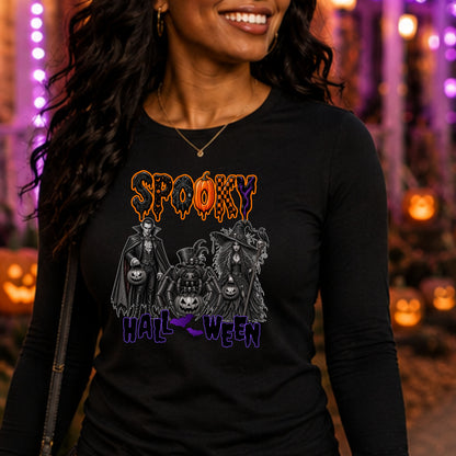 A woman wearing a black long-sleeve t-shirt with a 'Spooky Halloween' graphic print, set against a festive, blurred Halloween background with orange pumpkins and purple lights.