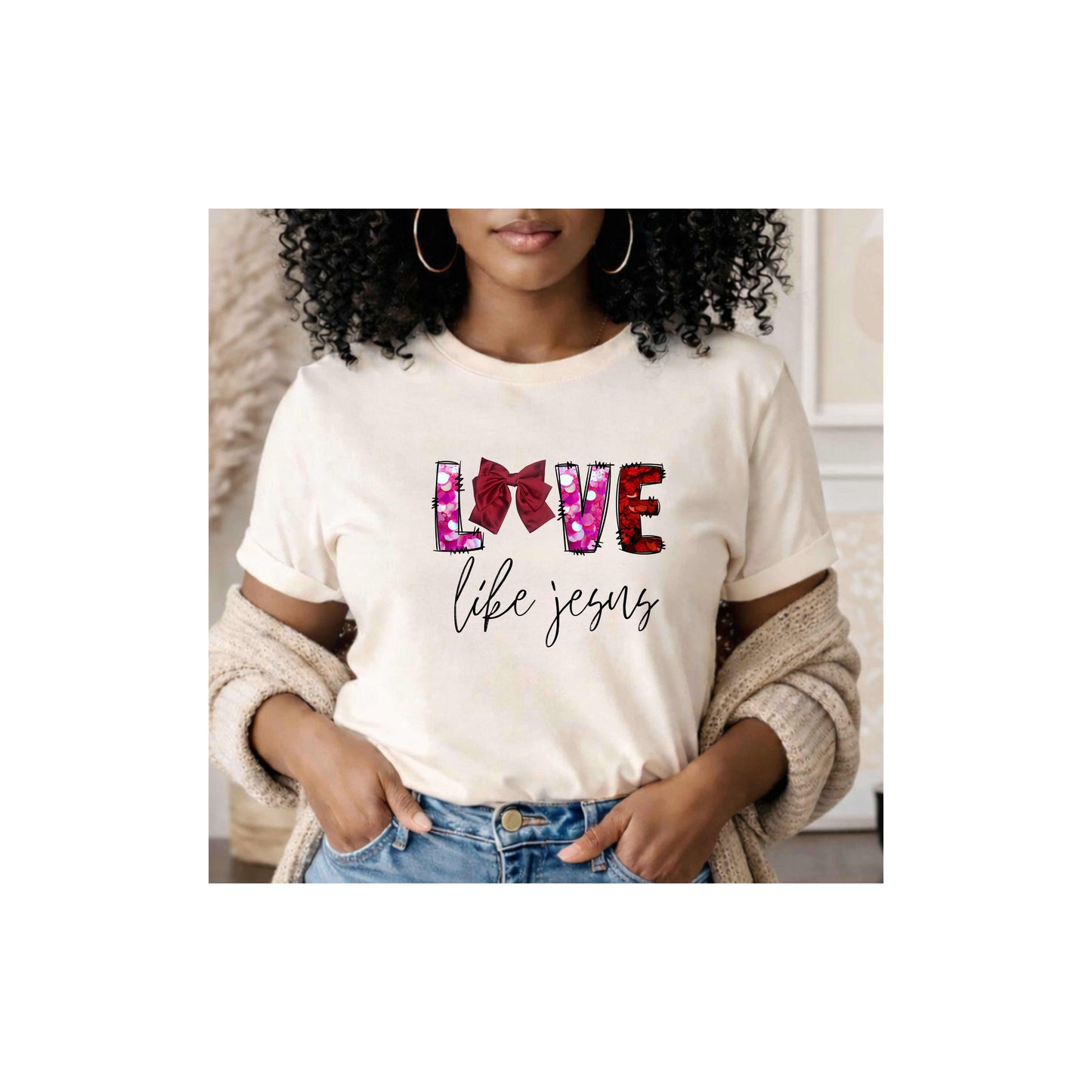 Woman wearing a white t-shirt with 'LOVE life Jesus' "Love Like Jesus" t-shirt featuring a stunning bow integrated into the word LOVE, standing in a neutral indoor setting.