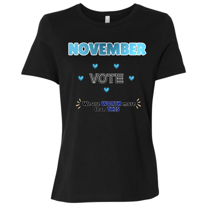 Bold November voting design on a Black T-Shirt featuring large blue gradient “NOVEMBER” lettering at the top, surrounded by blue heart accents. The center features outlined “VOTE” text, while the bottom reads “We are WORTH more than THIS,” with WORTH and THIS highlighted in blue and warm gold decorative accents on both sides. The design has a transparent background and high-contrast outlined typography set on a transparent background