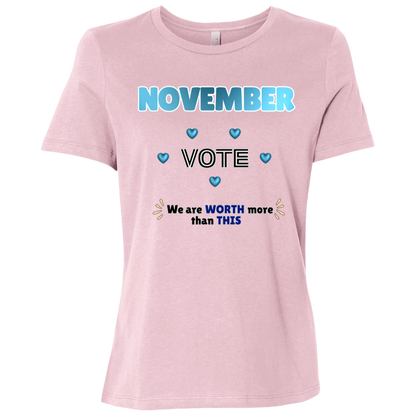 Bold November voting design on a Pink T-Shirt featuring large blue gradient “NOVEMBER” lettering at the top, surrounded by blue heart accents. The center features outlined “VOTE” text, while the bottom reads “We are WORTH more than THIS,” with WORTH and THIS highlighted in blue and warm gold decorative accents on both sides. The design has a transparent background and high-contrast outlined typography set on a transparent background
