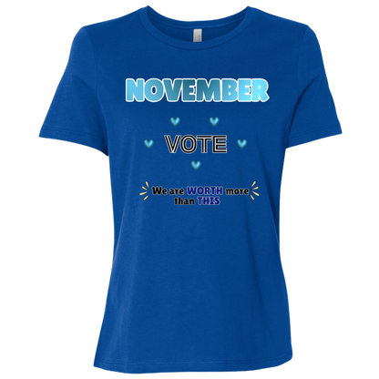 Bold November voting design on a True Royal T-Shirt featuring large blue gradient “NOVEMBER” lettering at the top, surrounded by blue heart accents. The center features outlined “VOTE” text, while the bottom reads “We are WORTH more than THIS,” with WORTH and THIS highlighted in blue and warm gold decorative accents on both sides. The design has a transparent background and high-contrast outlined typography set on a transparent background