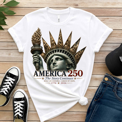 Commemorative artwork white t-shirt features the Statue of Liberty as a symbol of hope and resilience. Rising from her crown are detailed panels representing the values that continue to shape our nation: Opportunity, Freedom, Learning, Service, Creativity, Discovery, and Community with jeans, sneakers, black hat on a wooden background