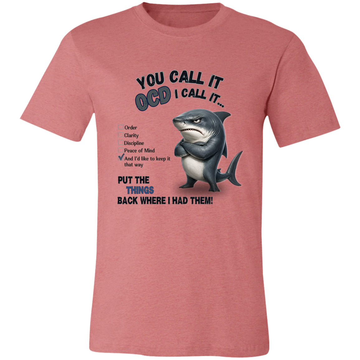 A unisex t-shirt in heather mauve, featuring a graphic print of a shark with crossed arms and the text 'YOU CALL IT OCD I CALL IT.' along with a checklist and the phrase 'PUT THE TRICKS BACK WHERE I HAD THEM!' on a transparent 