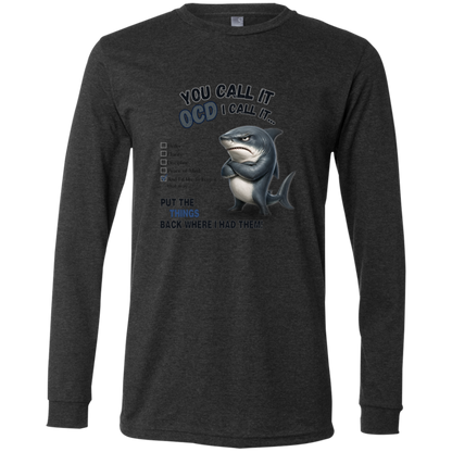 A men's long-sleeve crewneck t-shirt in dark grey heather, featuring a graphic print of a shark with crossed arms and the text 'YOU CALL IT OCD I CALL IT.' along with a checklist and the phrase 'PUT THE TRICKS BACK WHERE I HAD THEM!' on a transparent 