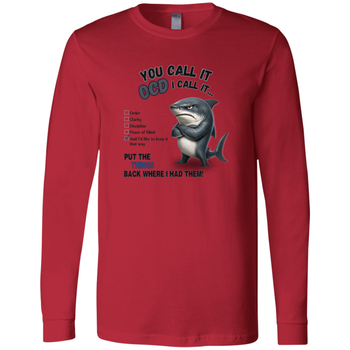 A men's long-sleeve crewneck t-shirt in red, featuring a graphic print of a shark with crossed arms and the text 'YOU CALL IT OCD I CALL IT.' along with a checklist and the phrase 'PUT THE TRICKS BACK WHERE I HAD THEM!' on a transparent 