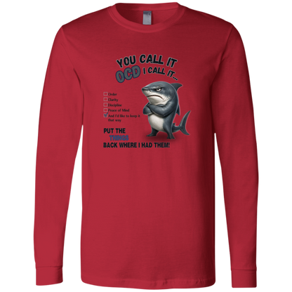 A men's long-sleeve crewneck t-shirt in red, featuring a graphic print of a shark with crossed arms and the text 'YOU CALL IT OCD I CALL IT.' along with a checklist and the phrase 'PUT THE TRICKS BACK WHERE I HAD THEM!' on a transparent 