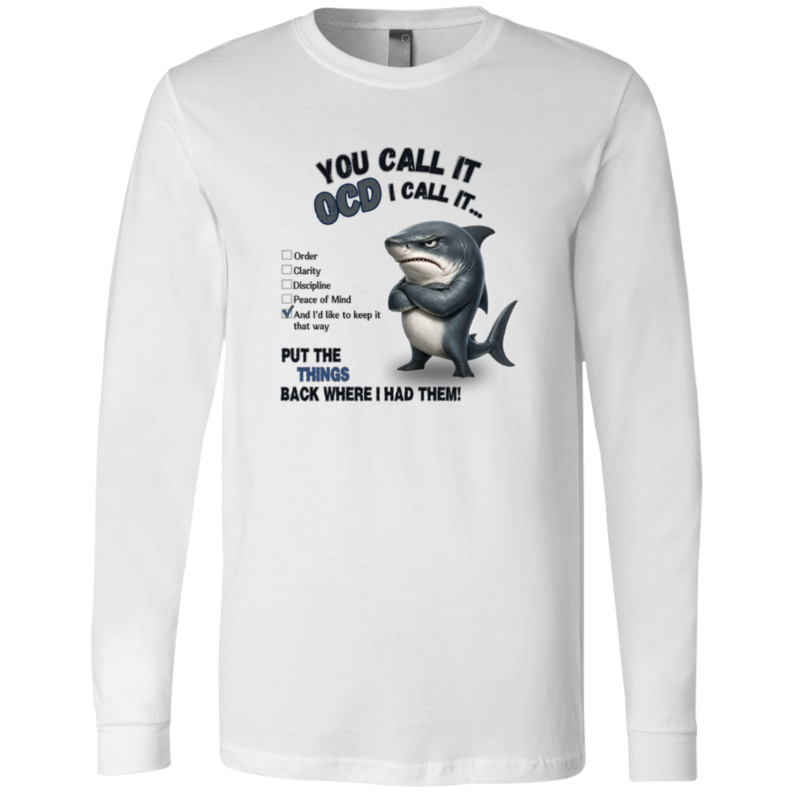 A men's long-sleeve crewneck t-shirt in white, featuring a graphic print of a shark with crossed arms and the text 'YOU CALL IT OCD I CALL IT.' along with a checklist and the phrase 'PUT THE TRICKS BACK WHERE I HAD THEM!' on a transparent 